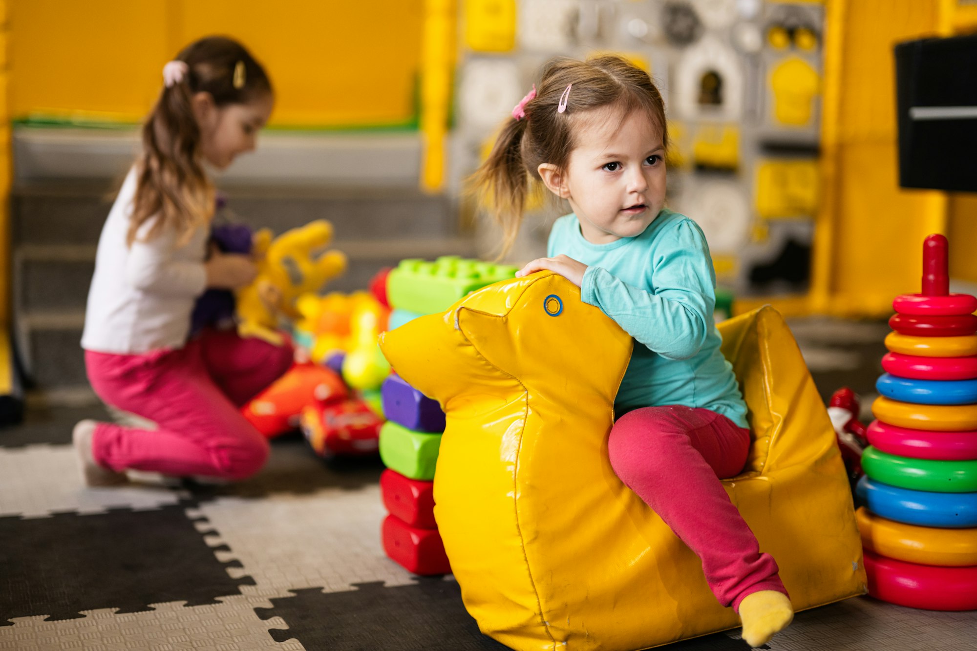 Baby girl swings on yellow paralon duck at kindergarten.